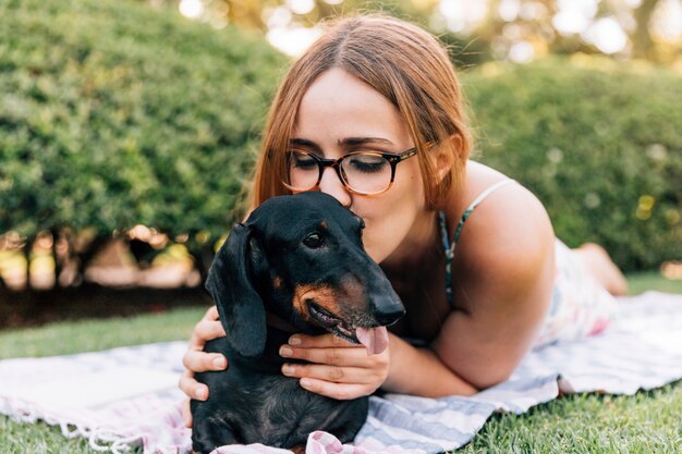 Junge Frau, die ihren netten Hund küsst