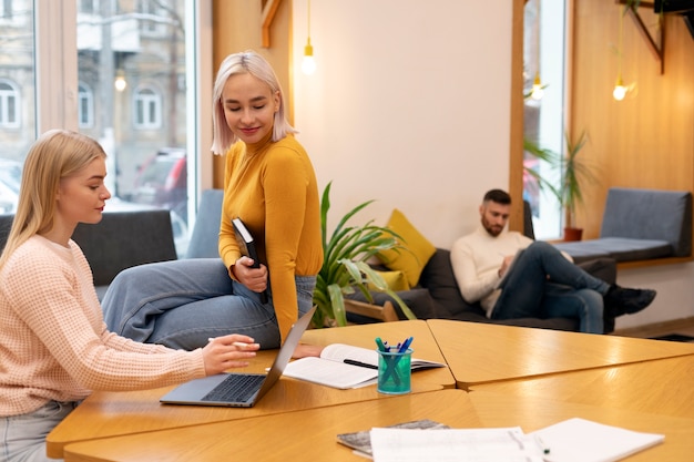 Kostenloses Foto junge frau, die ihrer freundin während der lernsitzung etwas auf ihrem laptop zeigt