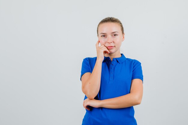 Junge Frau, die im blauen T-Shirt schaut und vernünftig schaut