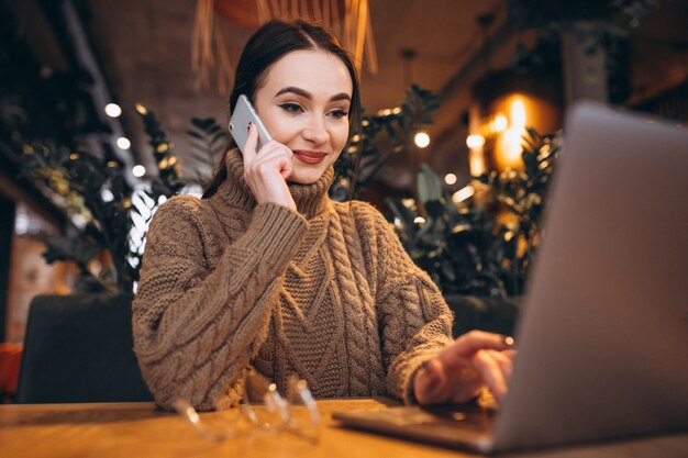 Junge Frau, die im Café sitzt und an Laptop arbeitet