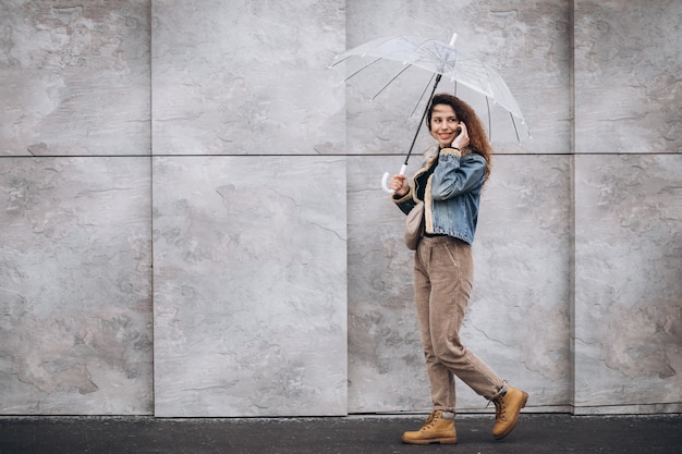 Junge Frau, die im Regen mit Regenschirm geht