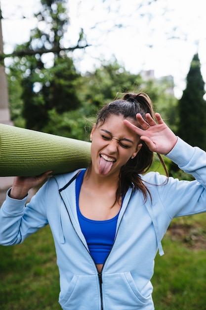 Junge Frau, die im Stadtpark hält Fitness-Teppich geht.