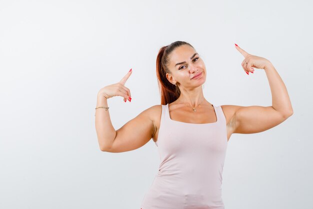 Junge Frau, die im Unterhemd zeigt und selbstbewusst, Vorderansicht schaut.