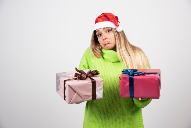 Junge Frau, die in den festlichen Weihnachtsgeschenken der Hände hält.