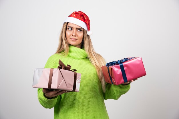 Junge Frau, die in den festlichen Weihnachtsgeschenken der Hände hält.