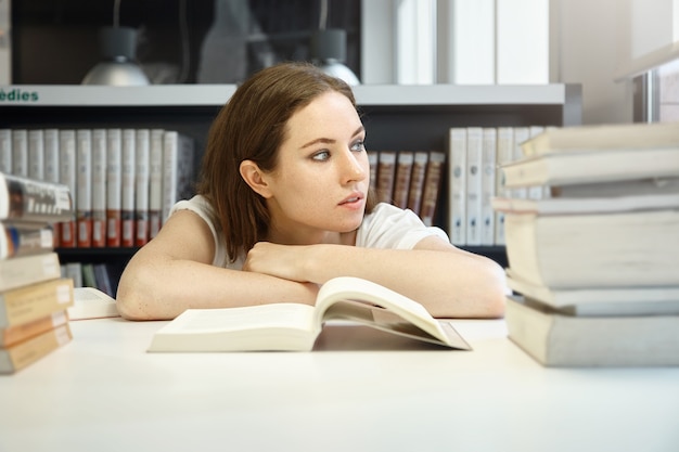 Junge Frau, die in der Bibliothek sitzt