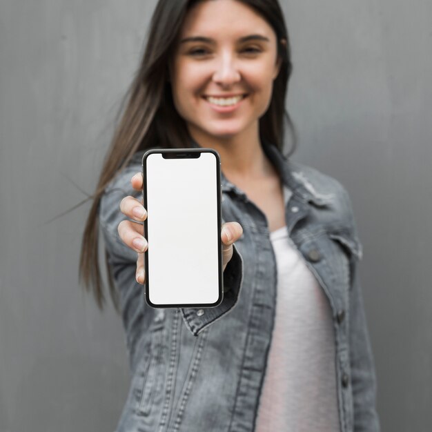 Junge Frau, die in der Hand Smartphone zeigt