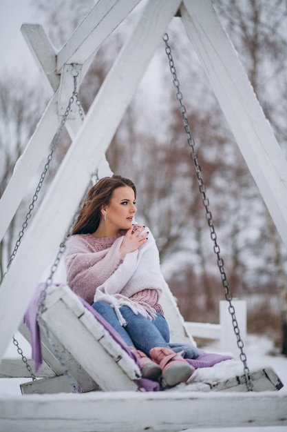 Junge Frau, die in einem Winterpark schwingt