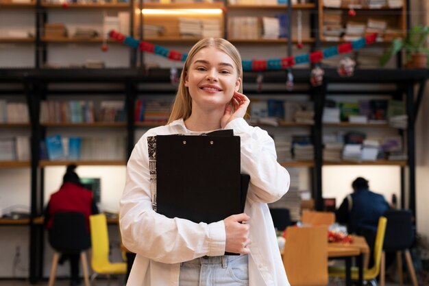 Junge Frau, die in einer Bibliothek nach Dokumenten sucht