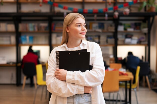 Junge frau, die in einer bibliothek nach dokumenten sucht