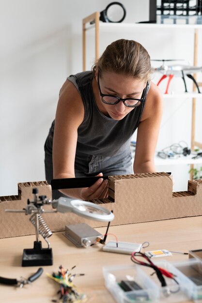 Junge Frau, die in ihrer Werkstatt für eine kreative Erfindung arbeitet