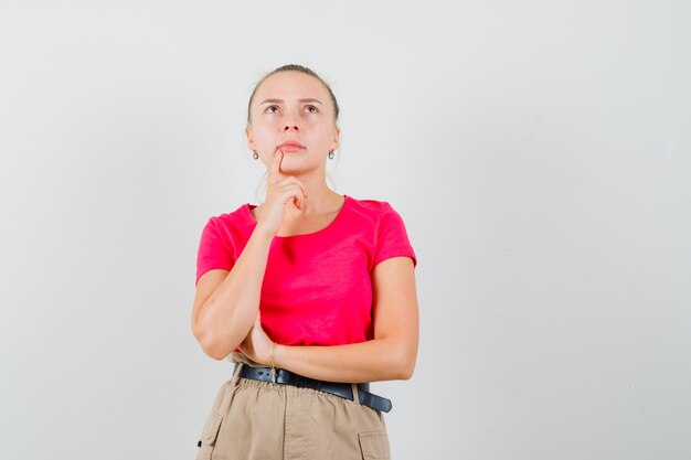 Junge Frau, die in T-Shirts und in der Hose nach oben schaut und nachdenklich schaut