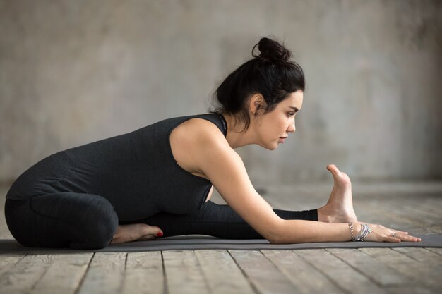 Junge Frau, die Janu Sirsasana Übung tut