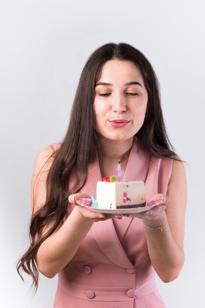 Junge Frau, die Kerze auf Kuchen heraus durchbrennt