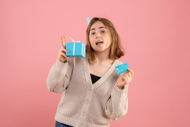 junge Frau, die kleine Weihnachtsgeschenke auf rosa hält