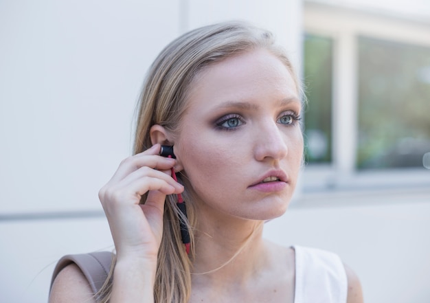 Kostenloses Foto junge frau, die kopfhörer in ihr ohr setzt