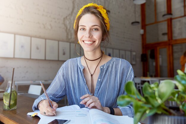 Junge Frau, die Kopftuch trägt und im Café studiert