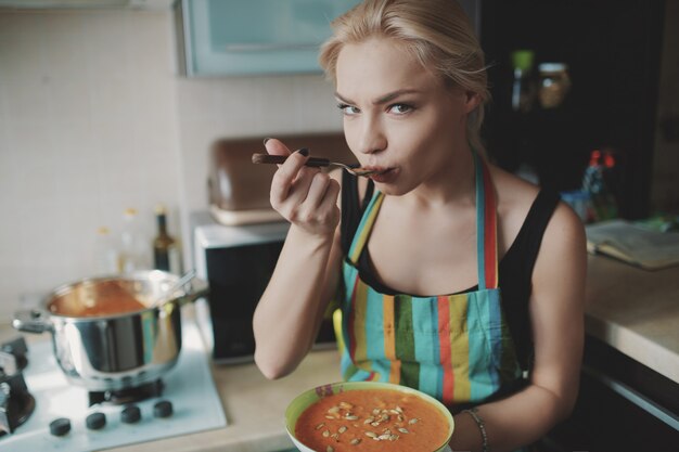 Junge Frau, die Kürbissuppe genießt