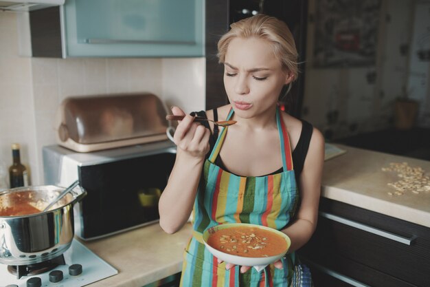 Junge Frau, die Kürbissuppe genießt