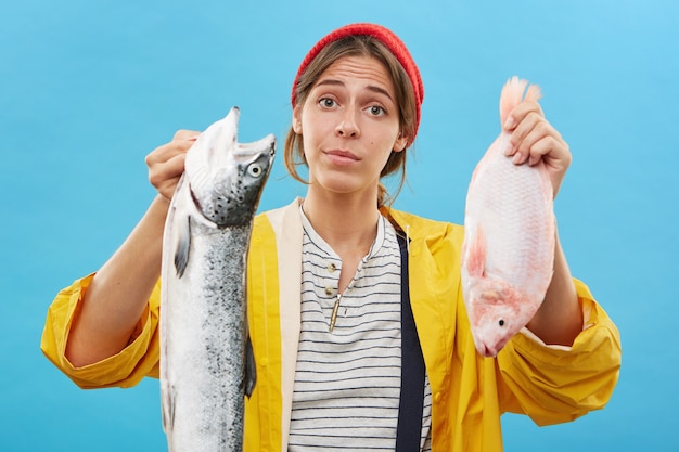 Kostenloses Foto junge frau, die lässig gekleidet ist und zwei fische in den händen hält