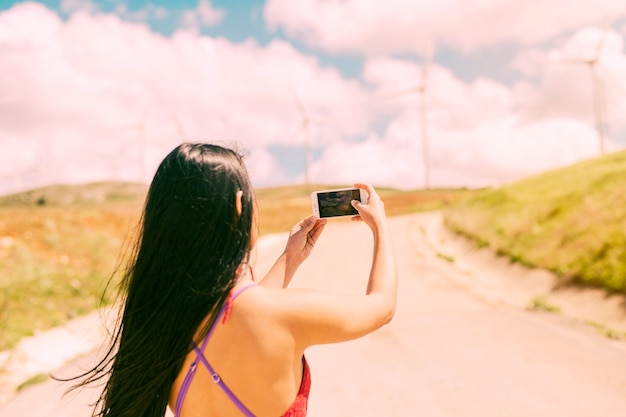 Junge Frau, die Landschaft am Telefon fotografiert