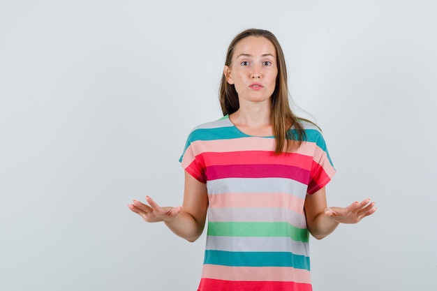 Junge Frau, die langsame Geste mit Handflächen in der T-Shirt-Vorderansicht zeigt.