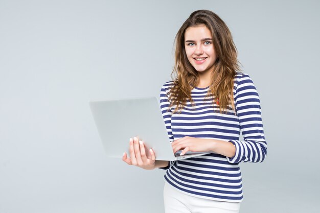 Junge Frau, die Laptop auf weißem Hintergrund hält