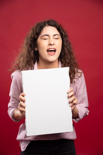 Junge Frau, die leere Leinwand hält.