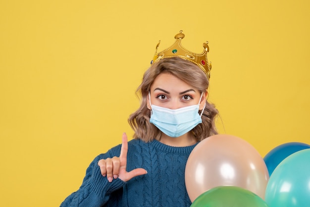 Kostenloses Foto junge frau, die luftballons in der sterilen maske auf gelb hält