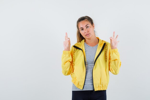 Junge Frau, die Meditationsgeste in Jacke, T-Shirt zeigt und selbstbewusst aussieht. Vorderansicht.