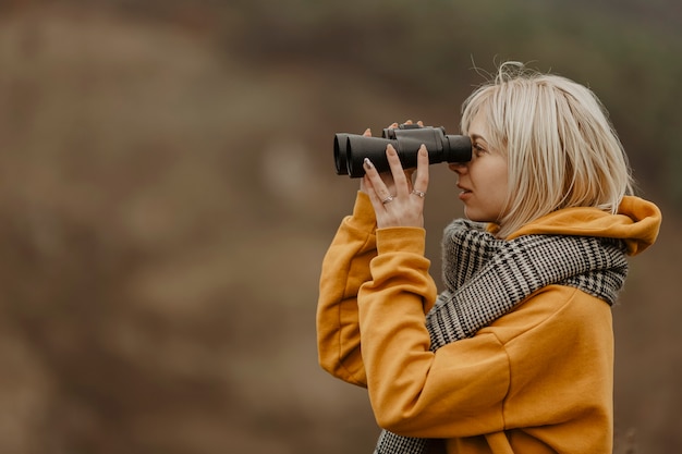 Junge Frau, die mit binokularem schaut