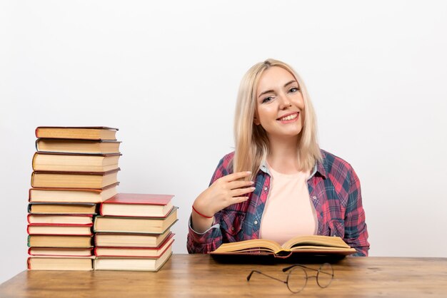 junge Frau, die mit Büchern auf Weiß sitzt