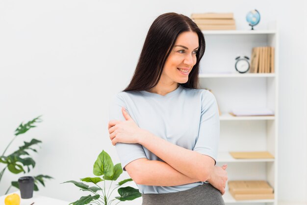 Junge Frau, die mit den gekreuzten Armen im Büro steht