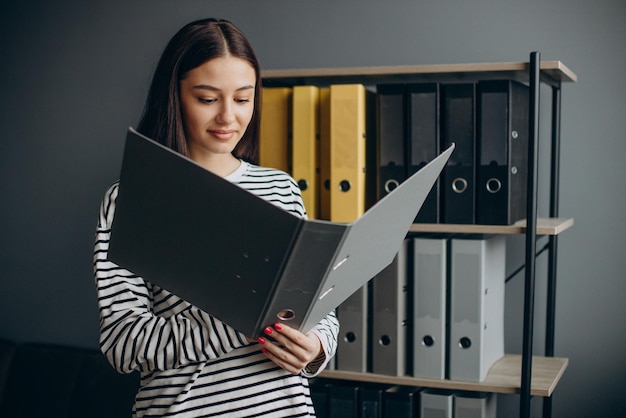 Junge Frau, die mit Dokumenten arbeitet und Archive überprüft