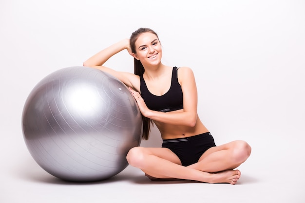 Junge Frau, die mit einem Ball arbeitet, der auf einer weißen Wand lokalisiert wird