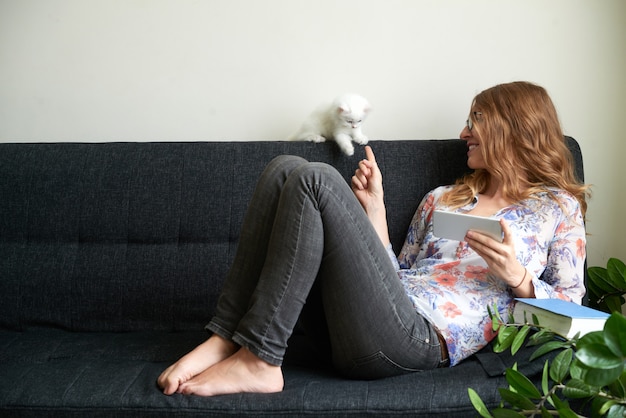 Junge Frau, die mit flaumigem weißem Kitten Horizontal Shot spielt