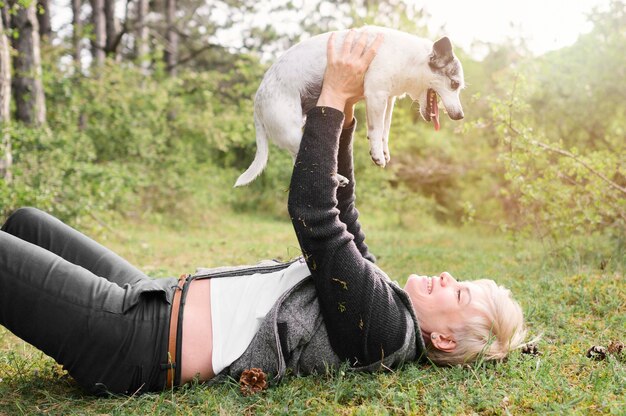 Junge Frau, die mit ihrem Hund draußen spielt