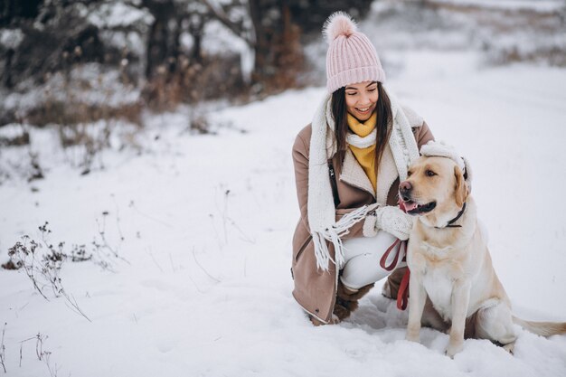 Junge Frau, die mit ihrem Hund in einem Winterpark geht