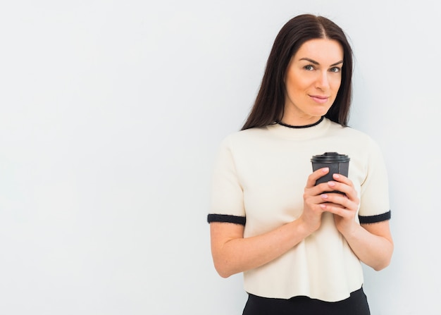 Junge Frau, die mit Kaffeetasse steht