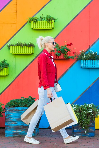 Junge frau, die mit taschen nahe wand geht