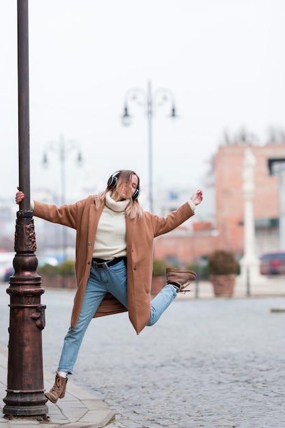 Junge Frau, die Musik auf Kopfhörern in der Stadt mit Kopienraum hört