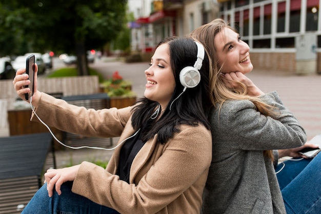 Junge Frau, die Musik auf Kopfhörern neben ihrem Freund hört