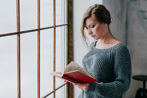 Junge Frau, die nahe Fenster liest