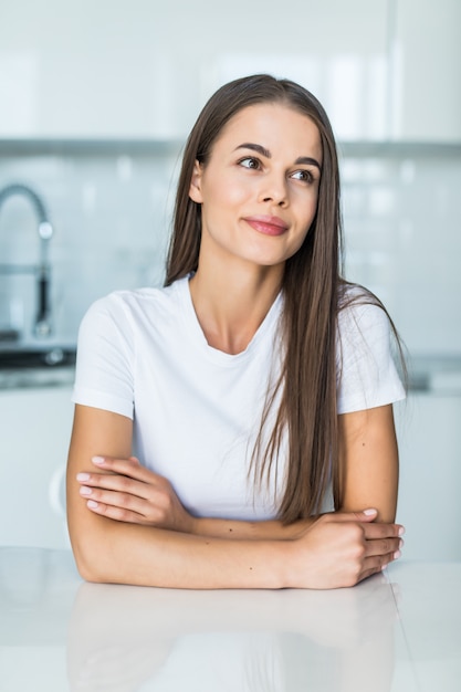 Kostenloses Foto junge frau, die nahe schreibtisch in der küche steht.