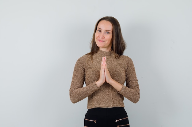 Kostenloses Foto junge frau, die namaste geste in der vorderansicht der goldenen bluse zeigt.