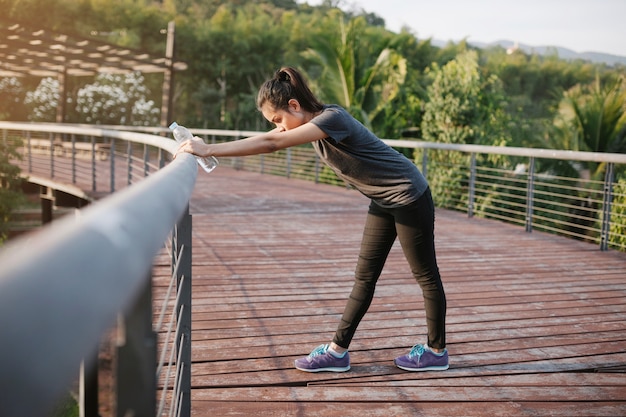 Junge Frau, die neben einem Geländer Stretching