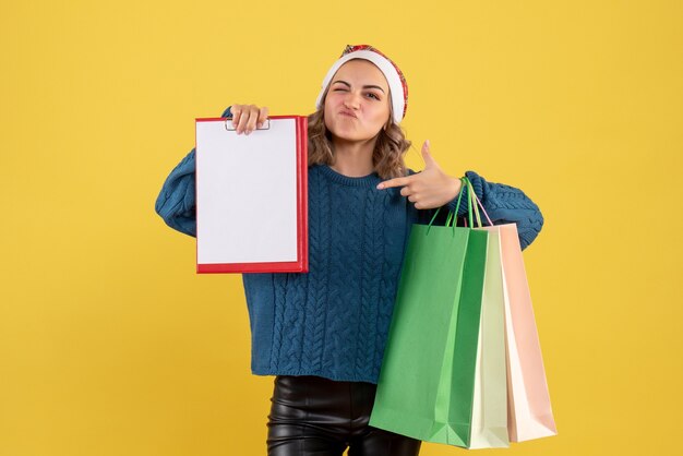 junge Frau, die Notiz und Pakete nach dem Einkauf auf Gelb hält
