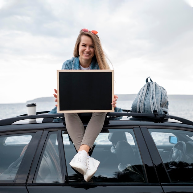 Junge Frau, die oben auf dem Auto sitzt