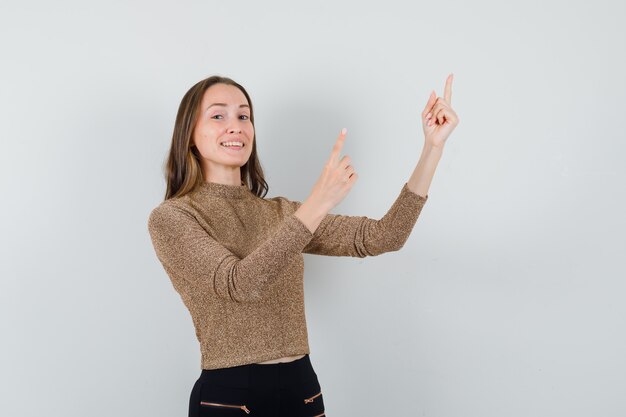 Junge Frau, die oben in Bluse, Rock zeigt und positiv schaut, Vorderansicht.