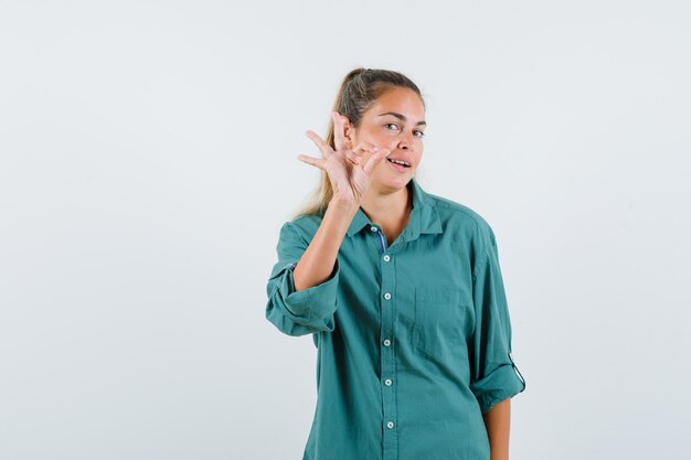 Junge Frau, die ok Geste im blauen Hemd zeigt und froh aussieht